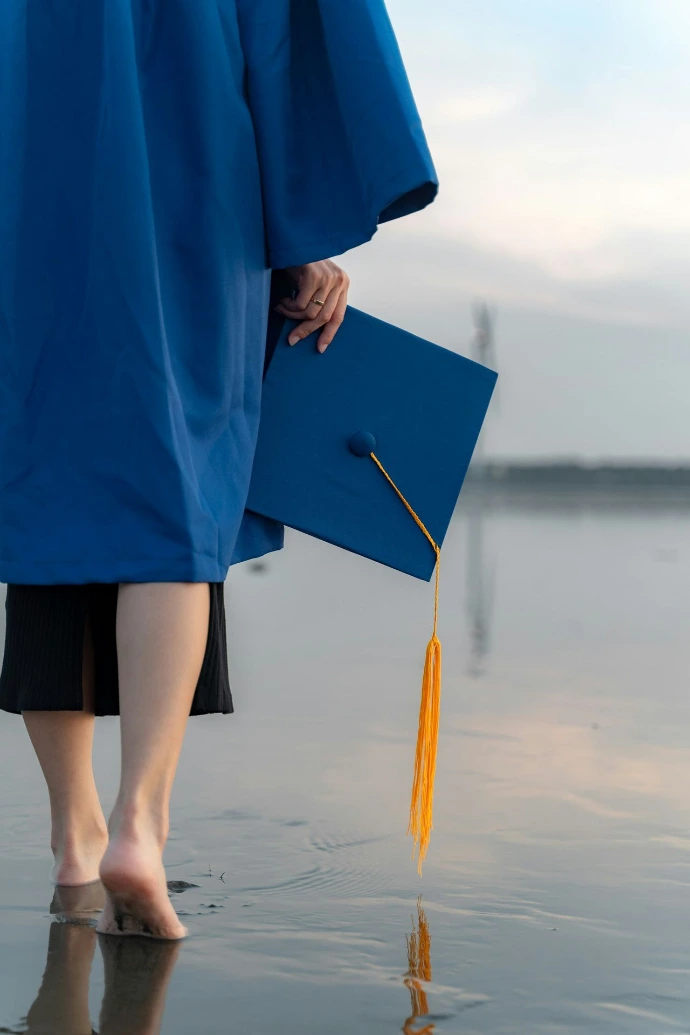 a person in a blue graduation gown holding a book